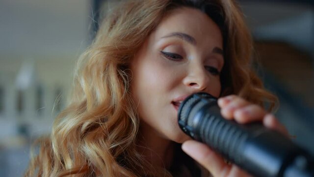 Woman singing song in microphone. Female singer performing musical song