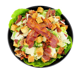 Bacon Caesar salad with romaine lettuce and parmesen cheese shavings served in a black dish isolated on a white background