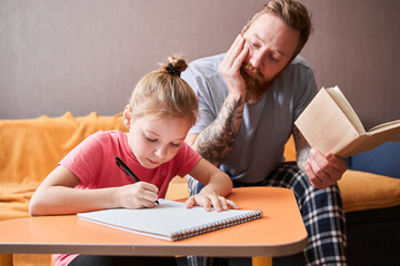 Father helping to little daughter with homework