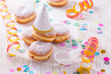 Traditional Berliner with party hat for carnival and party. German Krapfen or donuts with streamers...