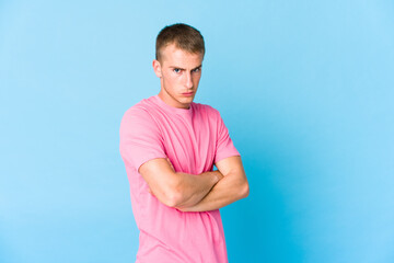 Young caucasian handsome man frowning face in displeasure, keeps arms folded.
