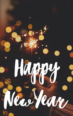 Happy New Year Greeting card. Happy New Year text handwritten on burning sparkler in female hand on background of christmas tree with lights. Seasons greetings, happy holidays