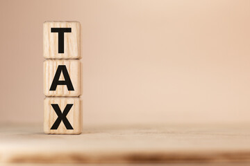 Word TAX on wooden blocks beige background
