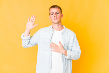 Young caucasian handsome man taking an oath, putting hand on chest.