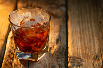 Fragrant whiskey with natural ice cubes on wooden background. Concept of alcoholic drinks. Advertising and promotion.