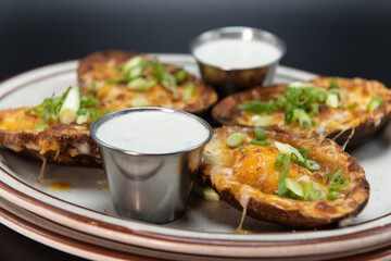 Side dish appetizer of steak stuffed potato skins served on a plate with sour cream dipping sauce.