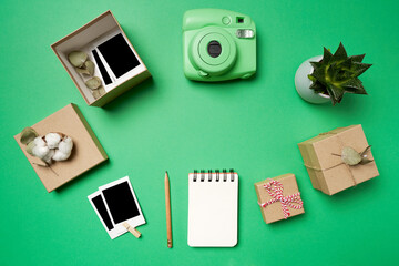 Flat lay analog camera, photos, photos in the box, boxes, notepad, pencil, succulents on green background. High quality photo