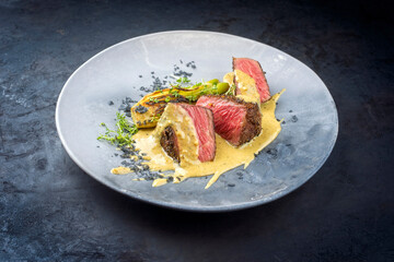 Modern style fried dry aged wagyu roast beef pepper steak with fennel and eggplant in pepper cream sauce served as close-up in a design plate