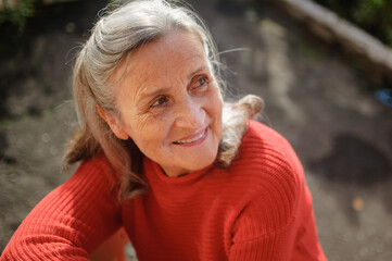 Close up portrait of a smiling senior woman with grey hair and face with wrinkles outdoors relaxing...