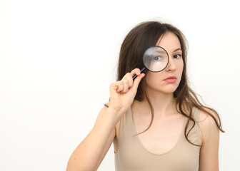 young beautiful woman with a magnifying glass near her eyes