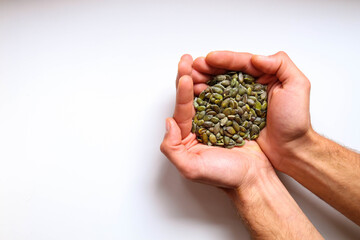 Full hands of peeled pumpkin seeds with white background.