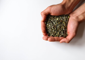 Full hands of peeled pumpkin seeds with white background.