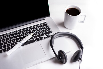 headset and syringe with antivirus on the computer keyboard, cup of coffee