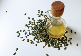 Raw papitas - no shell pumpkin seeds and pumpkin seed oil bottle on white.