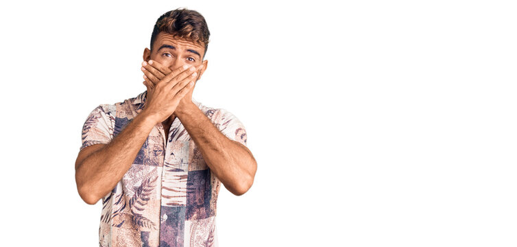 Young hispanic man wearing summer clothes shocked covering mouth with hands for mistake. secret concept.