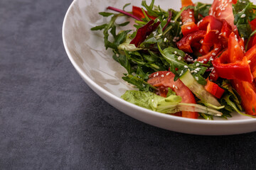 Vegan Spring Salad. Tomato, lettuce, dressing, bell peppers and avocados. Fork with vegetables and salad.
