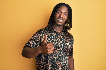 African american man with braids wearing leopard animal print shirt doing happy thumbs up gesture with hand. approving expression looking at the camera showing success.