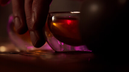 Tasting of oriental tea at a demonstration ceremony in the tea room. Hand picks up the cup from the table. Close-up and slowmotion.