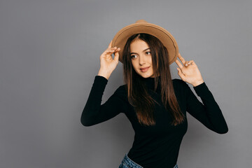 Pretty woman in black t-shirt and yellow hat on gray isolated background