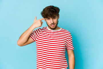 Young arab man on blue background showing a disappointment gesture with forefinger.