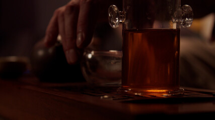 Close-up of a tea seller preparing to hold a tea tasting ceremony in his shop. Places cups, a porcelain teapot, and a tea flask on the chaban.