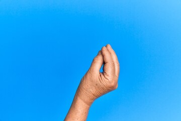 Hand of senior hispanic man over blue isolated background doing italian gesture with fingers...