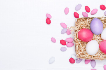 Easter eggs in the nest on white wooden background