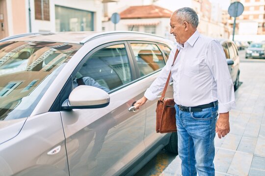 Senior man smiling happy opening car at the city.
