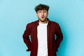 Young arab man on blue background being shocked because of something she has seen.