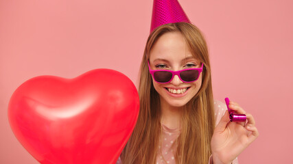 Young party woman holding heart shaped balloon. Isolated on pink background. High quality photo