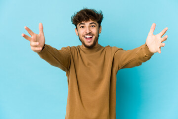 Young arab man on blue background celebrating a victory or success, he is surprised and shocked.