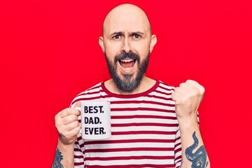 Young handsome man drinking mug of coffe with best dad ever message screaming proud, celebrating victory and success very excited with raised arms