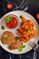 Masala chips on a white plate with tomato sauce and cutlets, on a dark marble table.