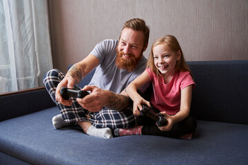 Father and daughter playing video games on console © Yakobchuk Olena