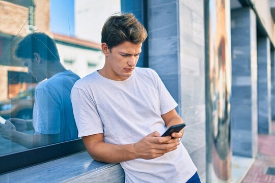 Young caucasian man smiling happy using smartphone at the city.