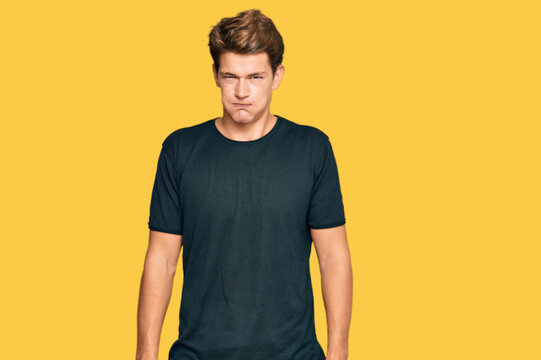 Handsome caucasian man wearing casual clothes puffing cheeks with funny face. mouth inflated with air, crazy expression.