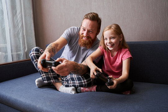 Father And Daughter Playing Video Games On Console