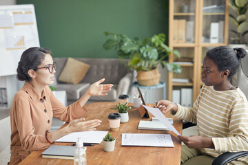 Side view portrait of two businesswomen talking and gesturing during job interview in office, copy...