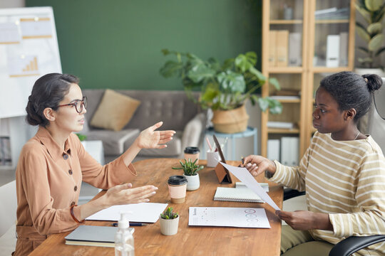 Side view portrait of two businesswomen talking and gesturing during job interview in office, copy space