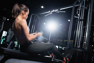 Obraz na płótnie Canvas young sportswoman exercising on rowing machine in gym
