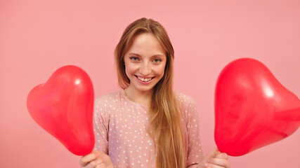Beautiful caucasian girl holding two heart shaped balloons. Love romance valentines day concept. High quality photo