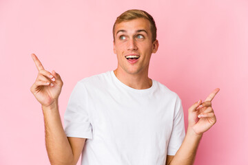Young caucasian handsome man pointing to different copy spaces, choosing one of them, showing with finger.