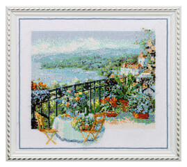 Embroidered picture in an openwork frame, outdoor cafe terrace overlooking the sea, cross-stitch on textile canvas, isolated on white background