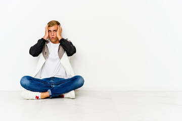 Young caucasian man sitting on the floor being shocked, she has remembered important meeting.