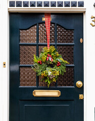 Christmas wreath on entrance vintage door outside. Veranda front door decorated by christmas festive wreath decor. Christmas outdoor exterior