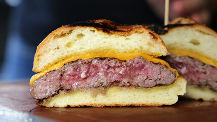 Hamburger. Made on the barbecue grill. With cheese, bacon, onion, pickle. On wooden background