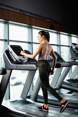 Fototapeta na wymiar athletic sportswoman in leggings exercising on treadmill in gym