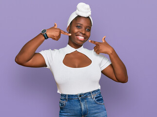 Young african woman with turban wearing hair turban over isolated background smiling cheerful showing and pointing with fingers teeth and mouth. dental health concept.