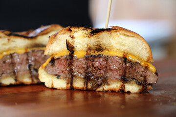 Hamburger. Made on the barbecue grill. With cheese, bacon, onion, pickle. On wooden background
