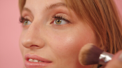 Obraz premium Beauty shot. Young caucasian woman with make up brush near her face. . High quality photo